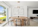 Bright dining area with modern table, chairs, and lighting fixtures near a large window offering natural light at 9485 Treasure Ne Ln, St Petersburg, FL 33702