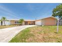 Single story home featuring a spacious driveway, two-car garage, and tropical landscaping at 9591 Commodore Dr, Seminole, FL 33776
