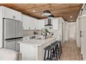 Modern kitchen featuring white cabinets, stainless steel appliances, an island and wood ceiling at 100 E Fern St, Tampa, FL 33604