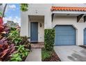 Close up of front entrance, showing blue door, lush landscaping and portion of blue garage at 102 S Moody Ave # 1, Tampa, FL 33609