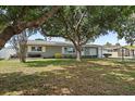 Single-story home with mature trees, green lawn, and a cheerful yellow bench enhancing its curb appeal at 11720 80Th Ave, Seminole, FL 33772