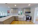Bright kitchen with stainless appliances, light gray cabinets, and a farmhouse sink beneath a window at 1200 47Th St N, St Petersburg, FL 33713