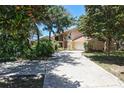 Charming two-story home with a stone chimney and attached two-car garage surrounded by mature trees and landscaping at 12929 Sugar Creek Blvd, Hudson, FL 34669