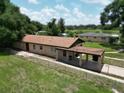 Wide shot of the home exterior with chain-link fence and covered carport at 14312 1St St, Dade City, FL 33525
