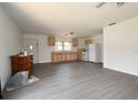 Open-concept kitchen and living area with new gray flooring, basic appliances, and natural wood cabinets at 14312 1St St, Dade City, FL 33525