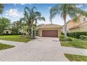 Inviting one-story home with a brick driveway, two-car garage, and mature palm trees, enhancing curb appeal at 18036 Java Isle Dr, Tampa, FL 33647