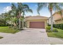 Beautiful one-story home featuring a brick driveway, two-car garage, and lush tropical landscaping with palm trees at 18036 Java Isle Dr, Tampa, FL 33647