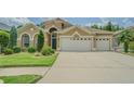 Beautiful home featuring manicured lawn, lush landscaping, and an attached three-car garage for ample parking at 2124 Rensselaer Dr, Wesley Chapel, FL 33543