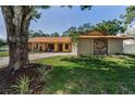 Charming single-story home featuring a stone facade, lush landscaping, and a long driveway leading to an attached garage at 3041 Oak View Dr, Palm Harbor, FL 34684