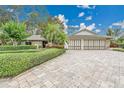 Beautiful home with manicured lawn, mature trees, and brick paver driveway at 3207 Hilltop Ln, Largo, FL 33770