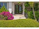 Close-up of the front door, surrounded by lush greenery and colorful flowers enhancing the home's curb appeal at 4807 W Longfellow Ave, Tampa, FL 33629
