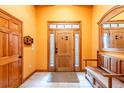 Bright foyer featuring tile flooring, a wooden front door with sidelights, and a bench at 6928 Cozumel Ct, Land O Lakes, FL 34637