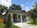 Attractive home featuring gray brick-like accents, a covered porch, and complemented by lush green landscaping at 7011 N 15Th St, Tampa, FL 33610