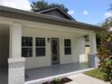 Inviting porch showcasing decorative pillars, a modern front door, and fresh landscaping at 7011 N 15Th St, Tampa, FL 33610