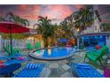 Inviting backyard pool area with lounge chairs, landscaping, and a colorful cabana at 722 Gulf Blvd, Indian Rocks Beach, FL 33785