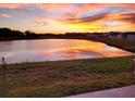Scenic pond view with colorful sunset reflected in the water, trees and homes along the shoreline at 9577 Sandy Bluffs Cir, Parrish, FL 34219