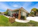 Home exterior featuring stone accents, a red tile roof, manicured lawn, and a well-kept side yard at 9909 San Mateo Way, Port Richey, FL 34668