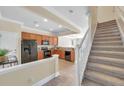 Bright kitchen with wooden cabinetry, black appliances, tile floors, and an adjacent staircase at 10217 Westpark Preserve Blvd, Tampa, FL 33625