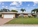 Inviting single-story home featuring a well-kept lawn, brick details, and a convenient two-car garage at 10387 Majestic Dr, Largo, FL 33774