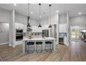 Open-concept kitchen with stainless appliances, quartz counters, island with seating, and wood flooring at 13167 Oldenburg Dr, Hudson, FL 34667