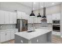 Bright kitchen with white cabinets, a large island, stainless steel appliances, and stylish pendant lights at 17404 Nokota Ave, Hudson, FL 34667