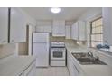 Clean and bright kitchen with white cabinets, appliances, and countertops, offering a functional cooking space at 1904 Canterbury Ln # 18, Sun City Center, FL 33573
