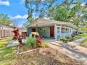 Inviting home exterior with a covered parking area, lush landscaping, and a welcoming red front door at 6700 14Th N St, St Petersburg, FL 33702