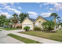 Charming yellow home featuring a well-manicured lawn, lush landscaping, and a paved driveway leading to an attached garage at 7833 Ontario Street Cir, Sarasota, FL 34243