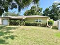 A ranch-style home with a green lawn and shrubbery at 9797 52Nd N Ter, St Petersburg, FL 33708