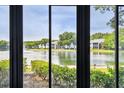 Water view with lush greenery and residential buildings, seen through a sliding glass door at 1109 Pine Ridge W Cir # C1, Tarpon Springs, FL 34688