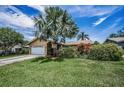 Charming single Gathering home with mature landscaping and a well-manicured lawn under a blue sky at 1281 Amberlea E Dr, Dunedin, FL 34698