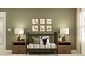 Bedroom featuring crib with animal prints on olive-green wall, side tables with lamps on carpet flooring at 13535 White Gold Run, Parrish, FL 34219