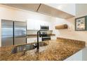 A close-up view of the kitchen featuring a granite countertop and stainless steel appliances at 16431 Enclave Village Dr # 16431, Tampa, FL 33647