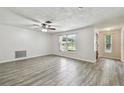 Bright living room featuring wood-look tile flooring, neutral walls, updated fixtures, and a large window at 1817 West Dr, Clearwater, FL 33755