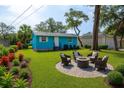 Beautiful backyard features a fire pit area, vibrant landscaping, lush green grass, and a cozy seating area at 1820 Douglas Ave, Clearwater, FL 33755
