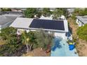 Aerial view of home with solar panels on roof, landscaped yard, and blue driveway at 2066 High Ridge Dr, Clearwater, FL 33763