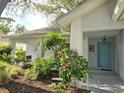 Landscaped front exterior featuring a covered entry and light-blue front door at 3509 Oak Lake Dr, Palm Harbor, FL 34684