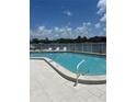 Inviting community pool with tiled deck, white fence, and beautiful water views at 376 Moorings Cove Dr # 6C, Tarpon Springs, FL 34689