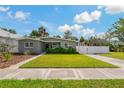 Charming single-story home featuring a well-manicured lawn, modern gray paint, and a white fence at 433 Pineapple St, Tarpon Springs, FL 34689