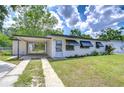 Inviting single-story home with awnings, a carport, landscaping, and a well-maintained lawn at 6004 S 82Nd St, Tampa, FL 33619
