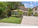 Charming two-story home boasts lush landscaping, a terracotta tile roof, and a brick driveway at 6008 Interbay Blvd, Tampa, FL 33611
