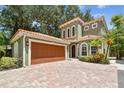 This charming house features a terracotta tile roof, a two-car garage, and a brick driveway at 6008 Interbay Blvd, Tampa, FL 33611
