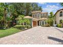 Charming two-story home boasts lush landscaping, a terracotta tile roof, and a brick driveway at 6008 Interbay Blvd, Tampa, FL 33611