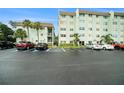 Exterior shot of condo buildings, a parking lot with multiple cars, and tropical landscaping at 801 83Rd N Ave # 107, St Petersburg, FL 33702