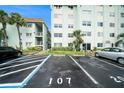 Exterior shot of condo buildings, parking spot number 107, multiple cars, and tropical foliage at 801 83Rd N Ave # 107, St Petersburg, FL 33702