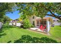 Spacious backyard patio with red chairs, lush lawn, and shaded area for outdoor relaxation at 8980 Antigua Dr, Seminole, FL 33777