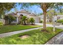 Charming single Gathering home with a lush front lawn and mature trees on a sunny day at 9047 Quail Creek Dr, Tampa, FL 33647