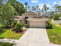 Charming single Gathering home with a lush lawn, mature trees and a two car garage at sunset at 9047 Quail Creek Dr, Tampa, FL 33647