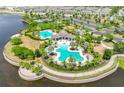 Aerial view showcasing the community pool and amenities surrounded by lush landscaping and a serene lake at 9423 Lemon Drop Loop, Sun City Center, FL 33573