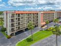 Aerial view of condo building with balconies surrounded by manicured lawns and mature palm trees at 9450 Harbor Greens Way # 207, Seminole, FL 33776